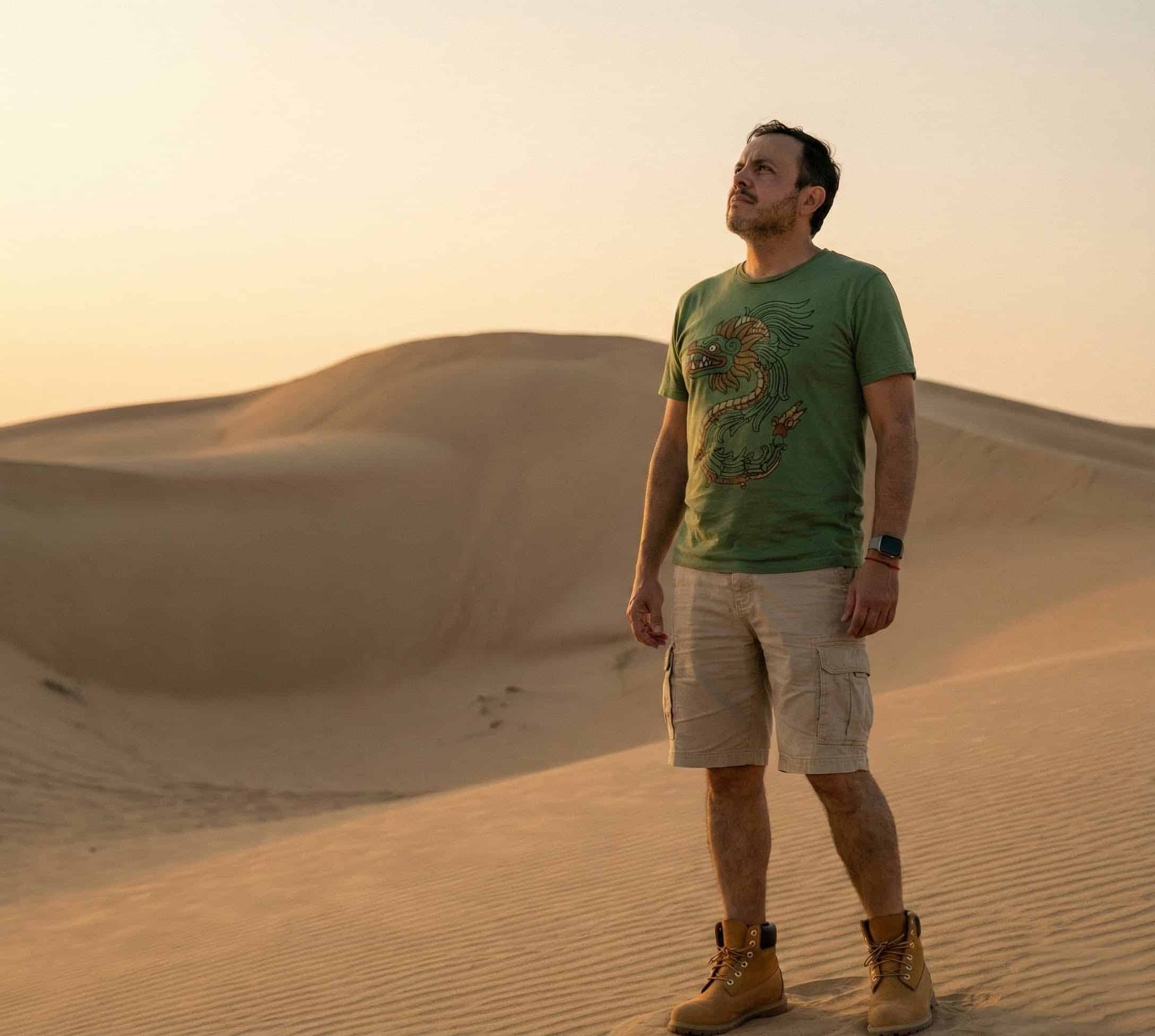 Hombre de pie en medio de un desierto, mirando al cielo luego de vivir un proceso de transformación gracias a su resiliencia desarrollada.