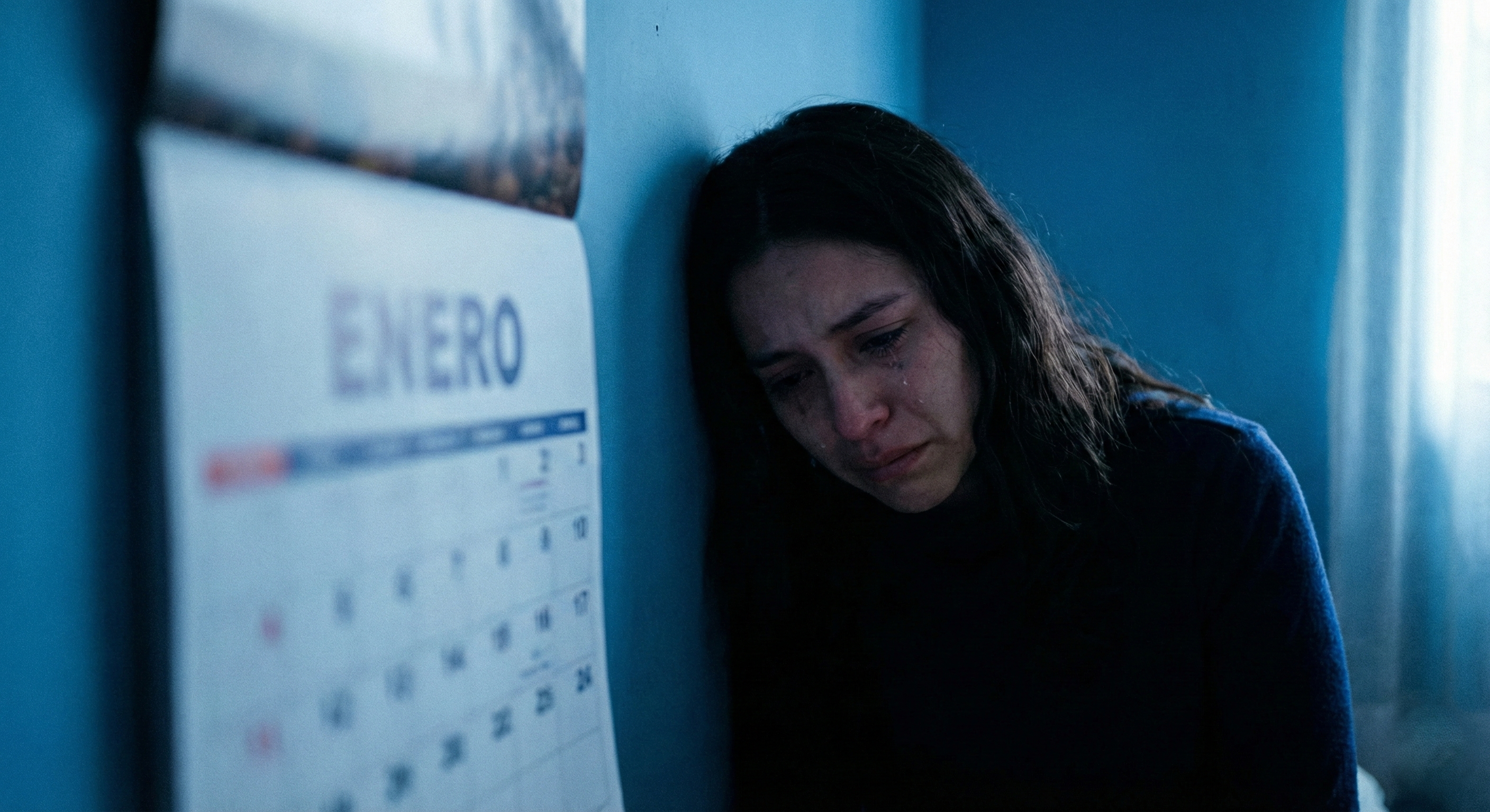 Mujer emocionalmente triste recargada en un muro y delante de ella un calendario que muestra el mes de ENERO, y marca muy posiblemente el Blue Monday