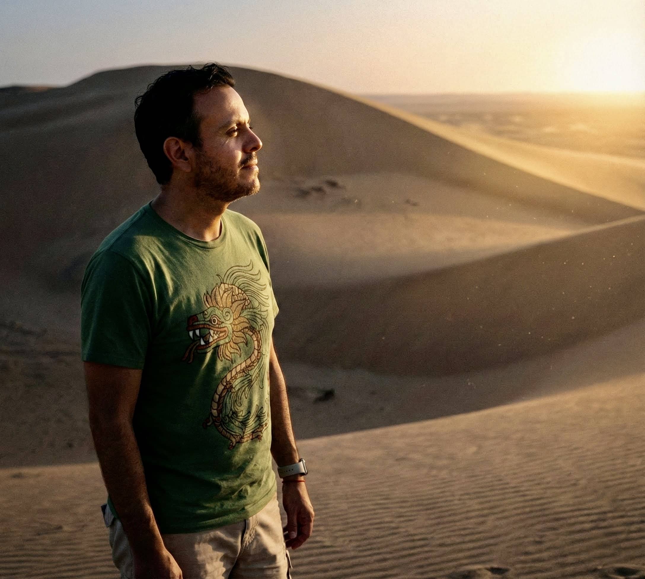 Juan Pablo García mira de perfil a un punto fijo mientras que detrás de él se muestran dunas y un atardecer que simbolizan el proceso de la resiliencia dentro de un desierto personal