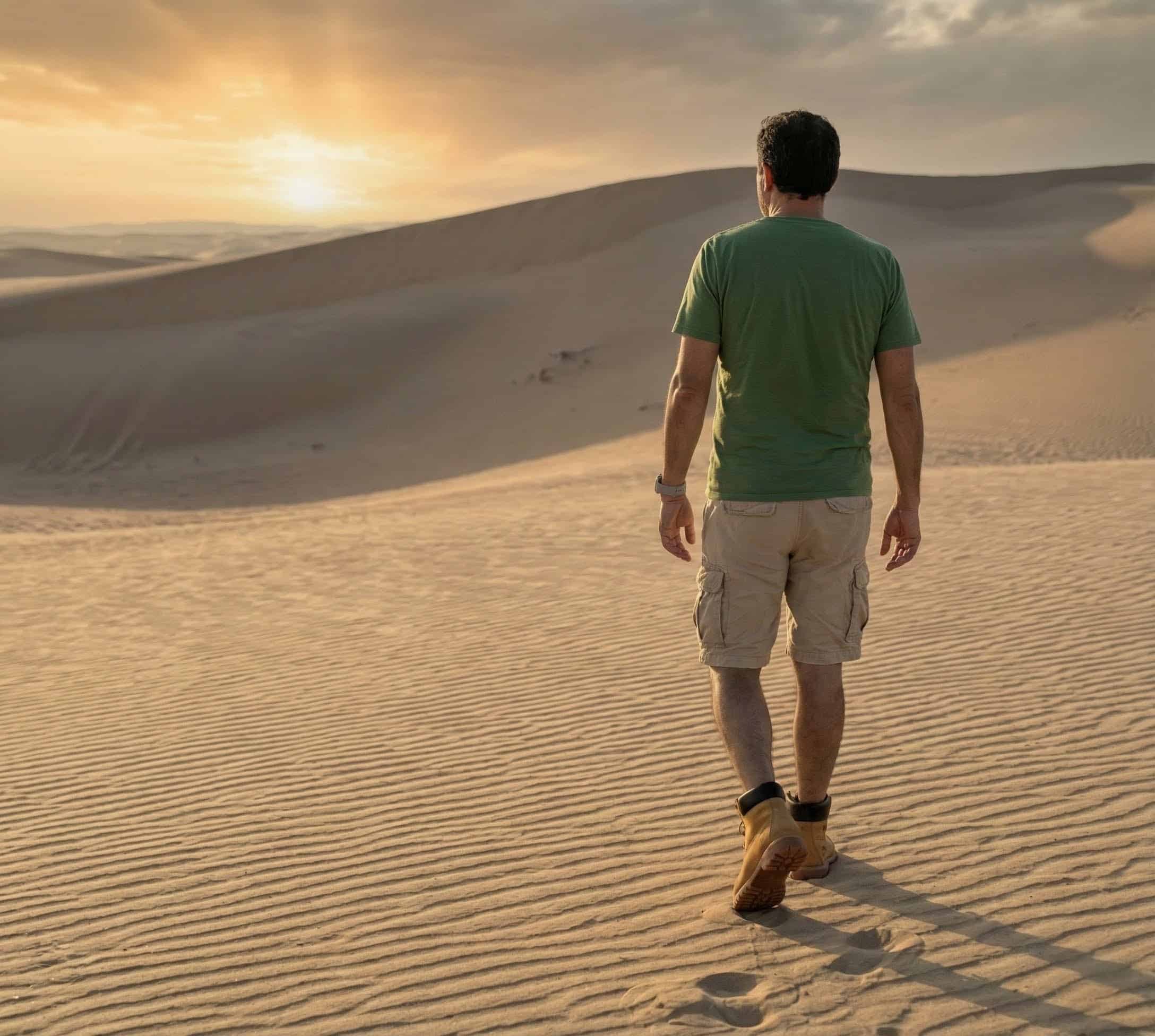 Hombre de espaldas caminando en su desierto personal en dirección al sol que representa la esperanza. 